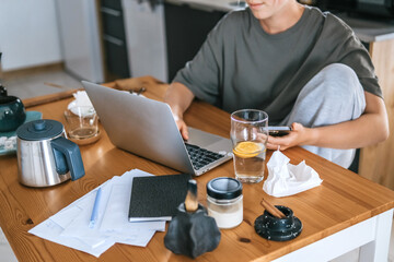  Gen Z woman working from home at cozy kitchen table with laptop and phone. Digital nomad lifestyle, mindfulness, remote work, balance, mental calm and modern freelancing