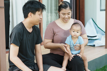 At home, a baby plays with their parents and aunt, sharing moments of laughter and occasional tears. The lively atmosphere reflects the warmth, joy, and emotional ups and downs of family life.
