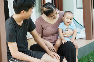 At home, a baby plays with their parents and aunt, sharing moments of laughter and occasional tears. The lively atmosphere reflects the warmth, joy, and emotional ups and downs of family life.
