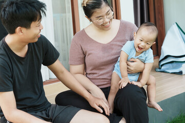 At home, a baby plays with their parents and aunt, sharing moments of laughter and occasional tears. The lively atmosphere reflects the warmth, joy, and emotional ups and downs of family life.

