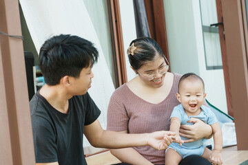 At home, a baby plays with their parents and aunt, sharing moments of laughter and occasional tears. The lively atmosphere reflects the warmth, joy, and emotional ups and downs of family life.
