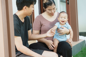 At home, a baby plays with their parents and aunt, sharing moments of laughter and occasional tears. The lively atmosphere reflects the warmth, joy, and emotional ups and downs of family life.
