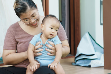 At home, a baby plays with their parents and aunt, sharing moments of laughter and occasional tears. The lively atmosphere reflects the warmth, joy, and emotional ups and downs of family life.
