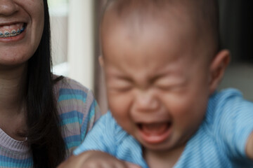 At home, a baby plays with their parents and aunt, sharing moments of laughter and occasional tears. The lively atmosphere reflects the warmth, joy, and emotional ups and downs of family life.
