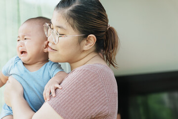 At home, a baby plays with their parents and aunt, sharing moments of laughter and occasional tears. The lively atmosphere reflects the warmth, joy, and emotional ups and downs of family life.
