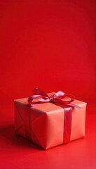 Obraz premium Small gift wrapped in paper with bow, red backdrop, celebration, red, present