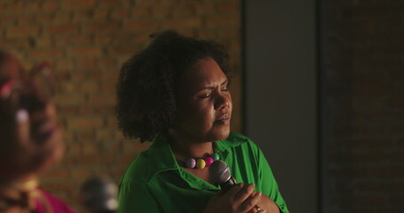 Singers passionately performing during evangelical church gathering, African descent women holding microphones, heartfelt worship, soulful vocal delivery, spiritual connection