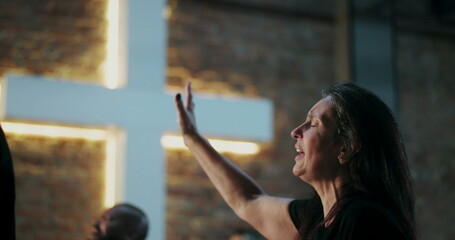 Woman in deep worship, raising her hand with eyes closed in prayer, emotional connection, Christian...