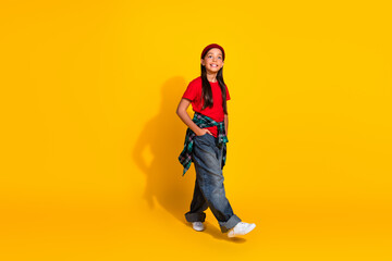 Fototapeta premium Happy young girl dressed casually with a red t-shirt and beanie smiling against a bright yellow background