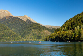 view of high mountain peaks densely covered with green thick forest. serene waters of the lake evoke a sense of peace. warm autumn day