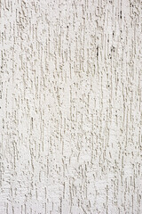 White plaster wall with vertical grooves, highlighting texture and pattern. Backgrounds, construction, or surface material concepts.