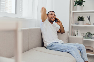 Smiling man enjoying a phone call, relaxed in comfortable home environment, expressing joy and...