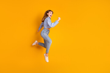 Joyful woman jumping in casual outfit on yellow background depicting happiness, vitality, and active leisure for promotional themes