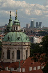 Fototapeta premium Dome architecture, featuring a stunning green patina in the foreground, offers a striking contrast to a modern city skyline that looms in the background under a dramatic cloudy sky