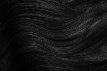Brunette or black hair. Female long dark hair in black. Beautifully laid curls. Closeup texture in a dark key. Hairdressing, hair care and coloring. Shading gray hair. Background with copy space.
