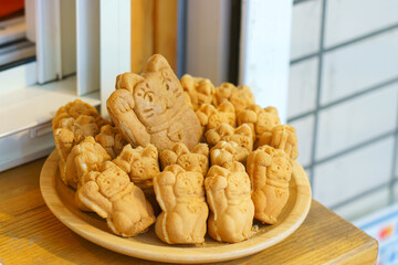Tokyo, Japan - Sep 30 2024, A close-up view of a bowl filled with Taiyaki pies in the form of a Maneki Neko, in the window of a cafe, Tokyo, Japan