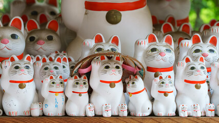 Tokyo, Japan - Sep 30 2024, A close-up view of many multi-sized white beckoning cat figure of Maneki neko with red ears and noses displayed at Gotokuji Temple, without people, at daytime, Tokyo, Japan