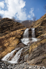 Fototapeta premium Waterfall of Lou Baseulh in Italy, Alps, Prali village in the mountains during spring on a sunny day