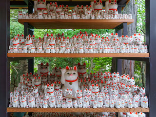 Tokyo, Japan - Sep 30 2024, A close-up view of many multi-sized white beckoning cat figure of Maneki neko with red ears and noses displayed at Gotokuji Temple, without people, at daytime, Tokyo, Japan