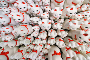 Tokyo, Japan - Sep 30 2024, A close-up view of many multi-sized white beckoning cat figure of Maneki neko with red ears and noses displayed at Gotokuji Temple, without people, at daytime, Tokyo, Japan
