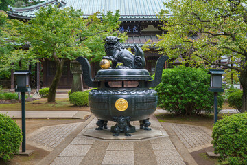 Tokyo, Japan - Sep 30 2024, Panoramic view of the bronze incense burner decorated with a lion statue, surrounded by trees, on road to Gotokuji Temple, without people, at daytime, Tokyo, Japan