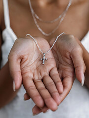 Cross necklace resting on palm, faith symbolism