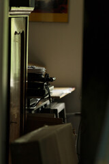 A cozy interior setting showcases a vintage record player surrounded by stylish furniture, along with scattered papers and various art pieces, inviting a glimpse into a relaxed living area