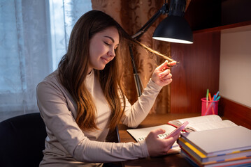 Teen girl smiling while texting during study break. Teenage girl replies to message on phone during...