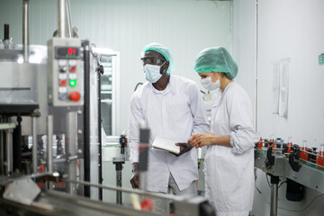 Two diverse factory workers are inspecting machinery inside a beverage production facility. focusing on quality control and efficient operation in an industrial manufacturing environment