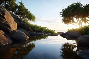 Tranquil sunset reflections in tropical natural pool surrounded by rocks and lush foliage