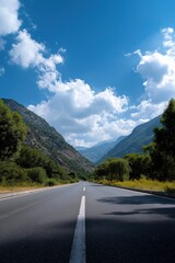 Fototapeta premium Scenic mountain road under blue sky with white clouds