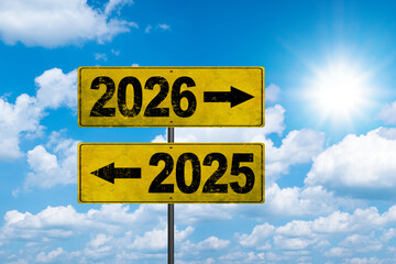 Road signs indicate the path to the new year 2026 and the old year 2025 on a blue sky, creative...