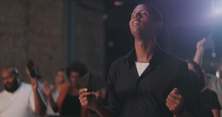 Diverse congregation raising offering envelopes during emotional prayer, immersed in worship and...
