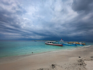 Obraz premium Beautiful seascape with touristic boats on sandy beach at Gili Meno island, Bali, Indonesia.&nbsp; Storm clouds, turquoise sea water. 