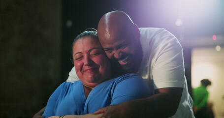 Person of African descent embraces woman in emotional moment of joy and laughter, tender hug, shared happiness, heartfelt connection, close-up of genuine human emotions