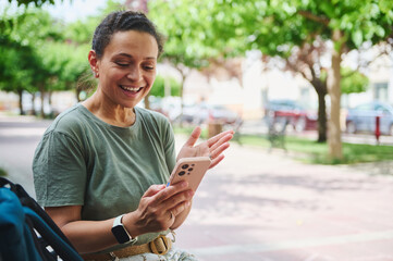Obraz premium Happy Woman Using Smartphone Outdoors Enjoying Video Call in Park