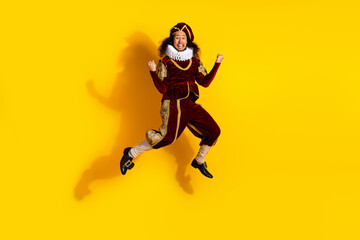 Young man jumping in an ornate nobleman costume against vibrant yellow background