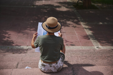Young Woman Reading Outdoors on Steps Wearing a Straw Hat