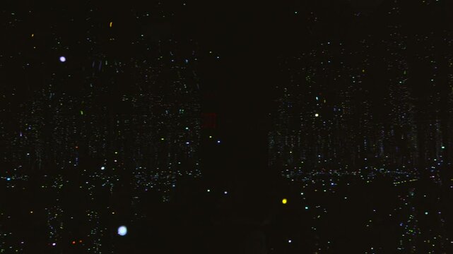 This video features a smooth panning shot inside a pitch-black mirrored room filled with thousands of suspended lights, creating the illusion of floating fireflies or a starry night sky. The immersive
