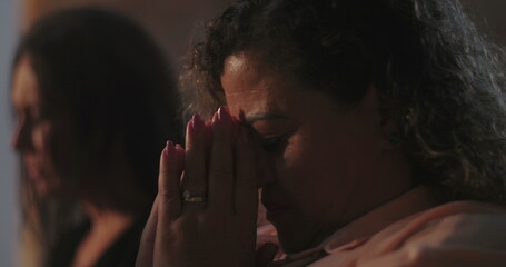 Woman with long dark hair in silent contemplation, eyes closed, peaceful and reflective expression during spiritual event, focus on inner faith and meditation