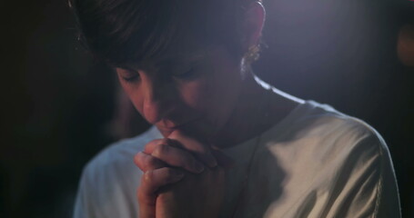 Woman bowing head in prayer, hands clasped in silent spiritual reflection, peaceful worship moment, serene focus on inner faith and connection to devotion