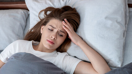 Mental health disorders. Top view of unhappy Caucasian woman lying in bed, suffering from...