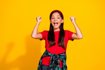 Adorable happy young girl celebrating success wearing casual fashion on a vibrant yellow background