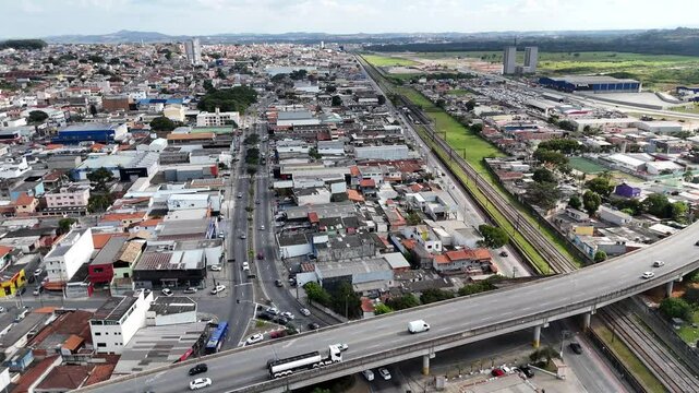 Vista a&eacute;rea panor&acirc;mica de Mogi das Cruzes com &aacute;reas residenciais, pr&eacute;dios e vegeta&ccedil;&atilde;o ao fundo. Cidade em desenvolvimento com &aacute;reas urbanas e verdes