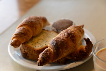 Plate with croissants buns and sponge cake for breakfast