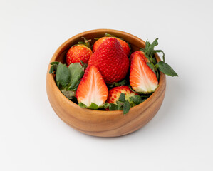 Group of strawberries in a wooden bowl on a white background
