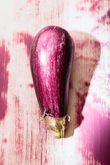 Brightly painted graffiti of an eggplant adorns a weathered wall in a bustling urban alley, showcasing the creativity of local artists. This unique art blends vibrant colors with the city vibe