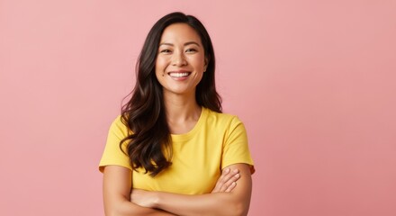 Cheerful woman with crossed arms in yellow shirt on pink background