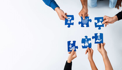 Hands holding colorful puzzle pieces with various business icons symbolize teamwork and collaboration in a professional setting, ideal for corporate visuals. Amity