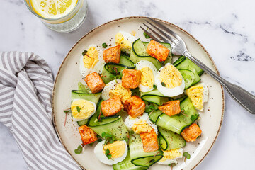 Delicious salmon and egg salad served on a plate with fresh cucumber and herbs for a healthy meal at lunchtime
